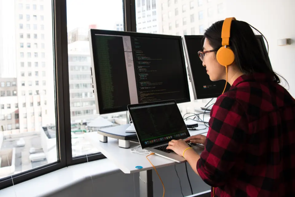 Especialista en WordPress revisando el código de una web en dos monitores