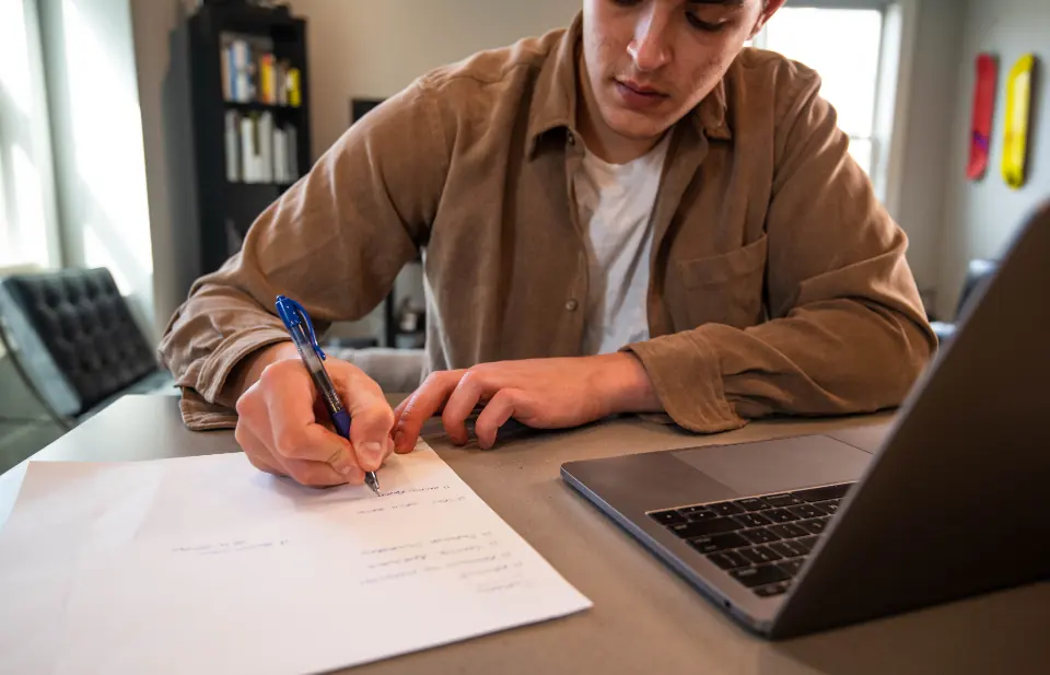 Especialista tomando notas mientras repara una web WordPress en su portátil