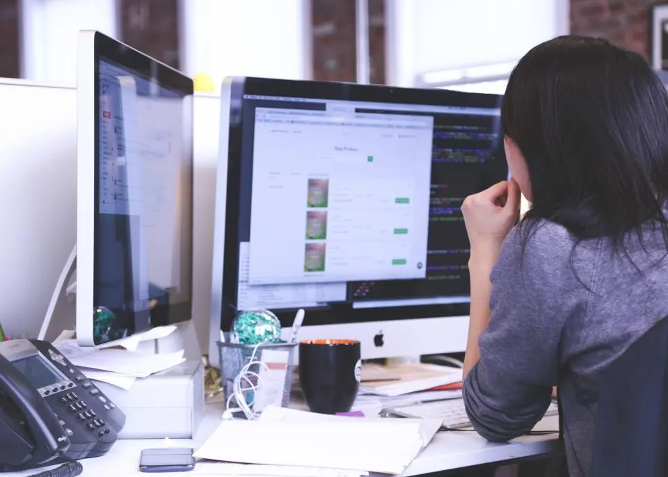 Mujer revisando una web restaurada en dos monitores