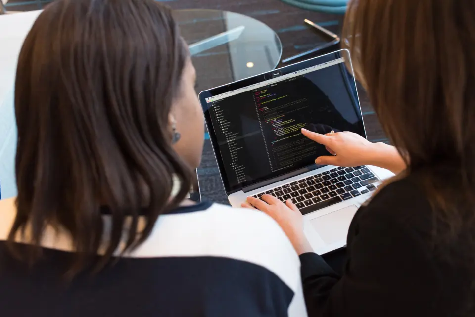 Dos personas de soporte revisando juntas una web en un portátil
