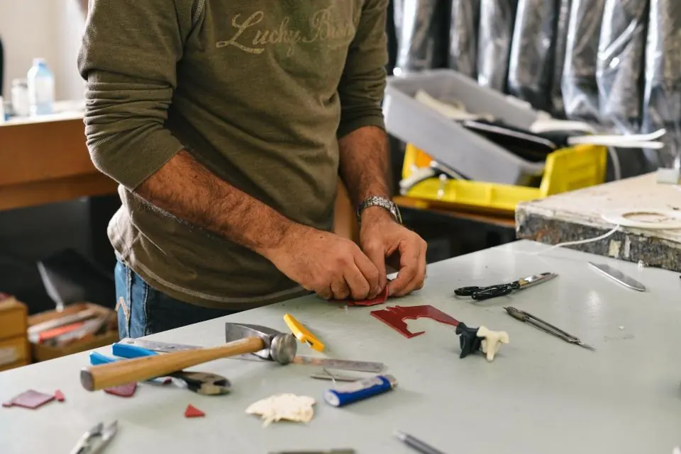 Persona reparando un objeto en su mesa de trabajo